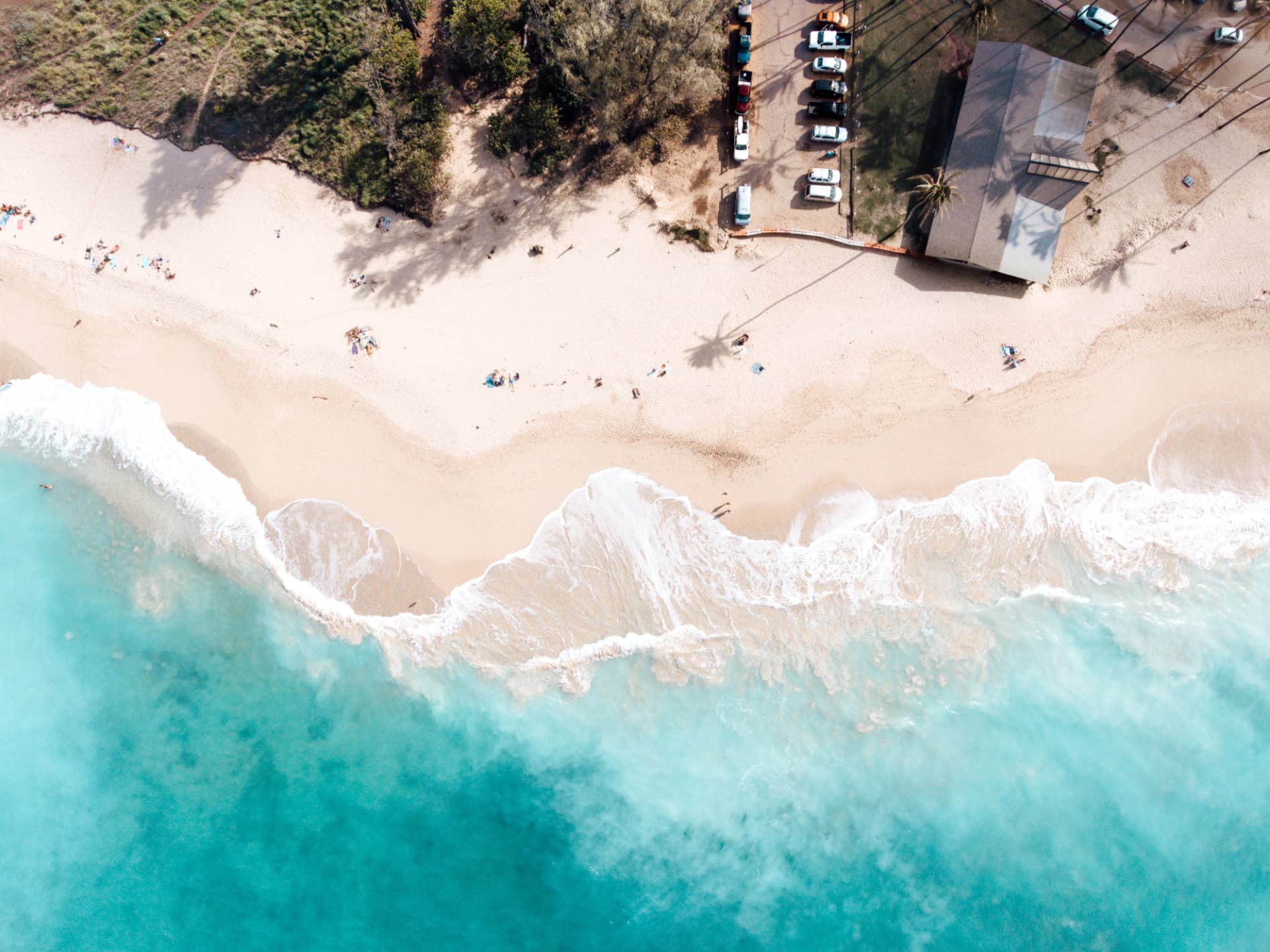 Aerial view of a shoreline with soft surf and a quiet beach
