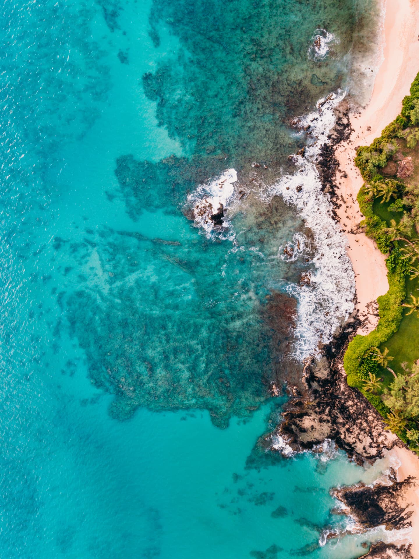 Aerial view of reef patterns beneath clear turquoise water